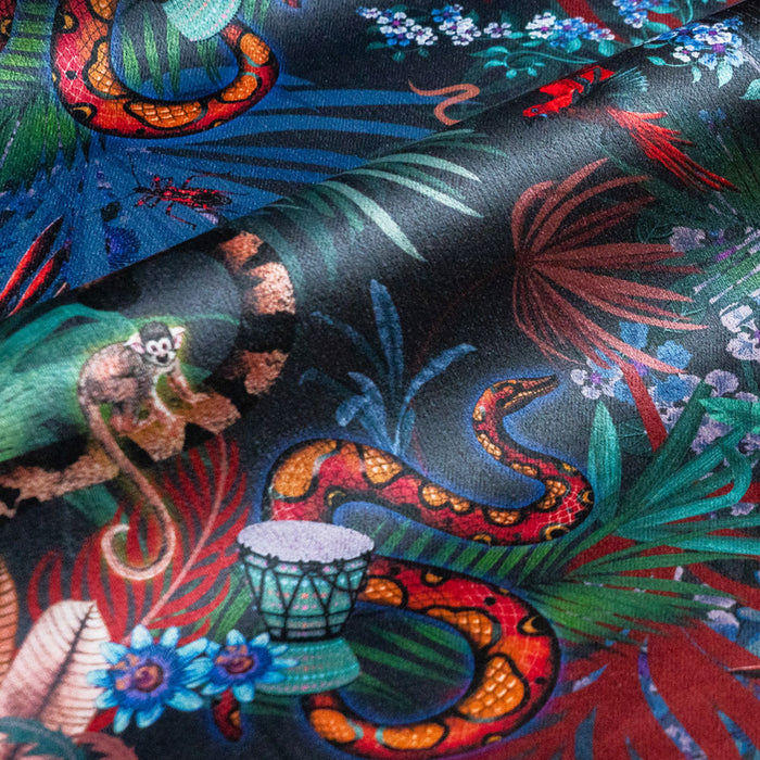 Detail of the macaw, monkey and rainbow boa on midnight blue jungle print velvet furnishing fabric