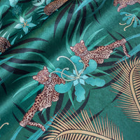 Detail of the leopards lazing among flowers on green and gold ornamental pattern velvet furnishing fabric