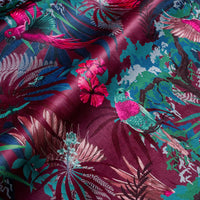 Rippled lengths of Rainforest Rush hot pink and claret tropical bird print velvet fabric for upholstery and cushions