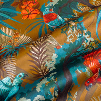 Close-up of the tropical birds on Rainforest Rush mustard yellow patterned velvet upholstery fabric