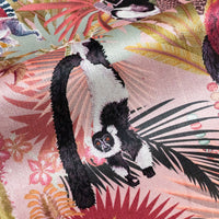 Close-up of swinging lemur on Treetop Tango lemur print velvet fabric in dawn pink