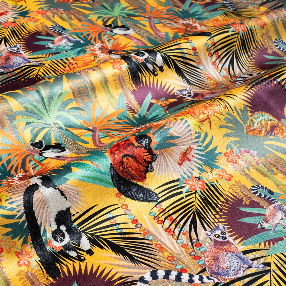 Rippled lengths of Treetop Tango sunshine yellow lemur print velvet fabric showing the sheen catching the light